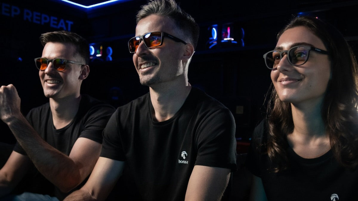 deux hommes et une femme qui ont l'air heureux de porter des lunettes horus x et de jouer à des jeux vidéo.