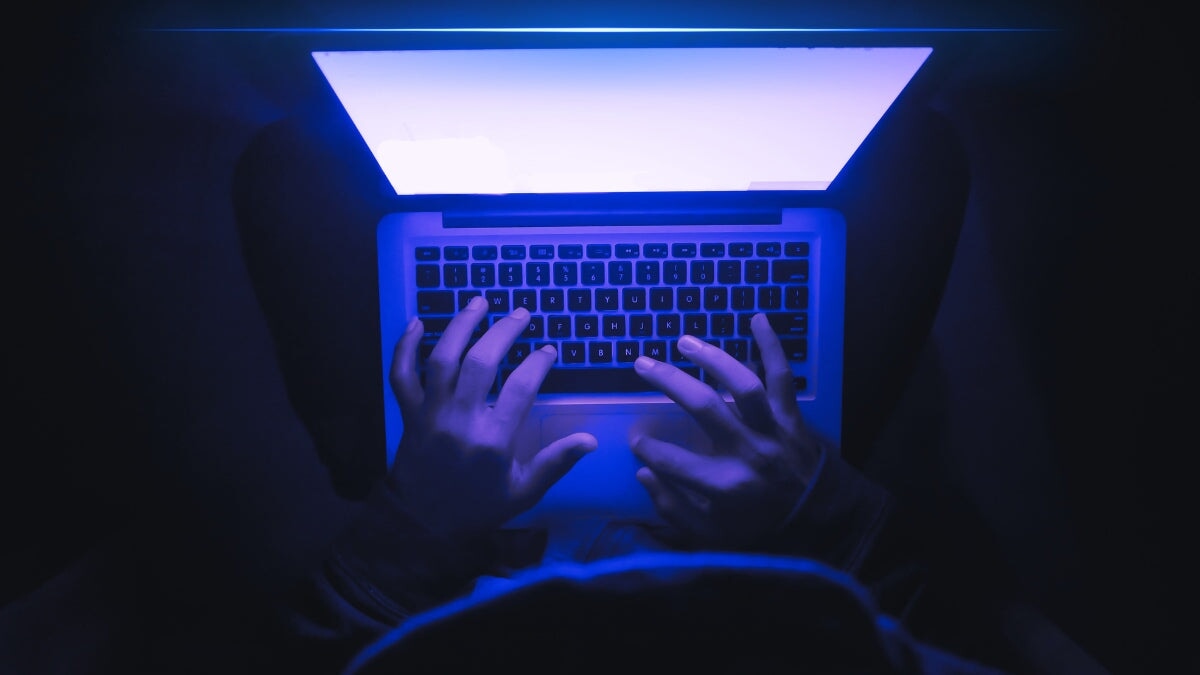 homme travaillant dans le noir avec son ordinateur portable