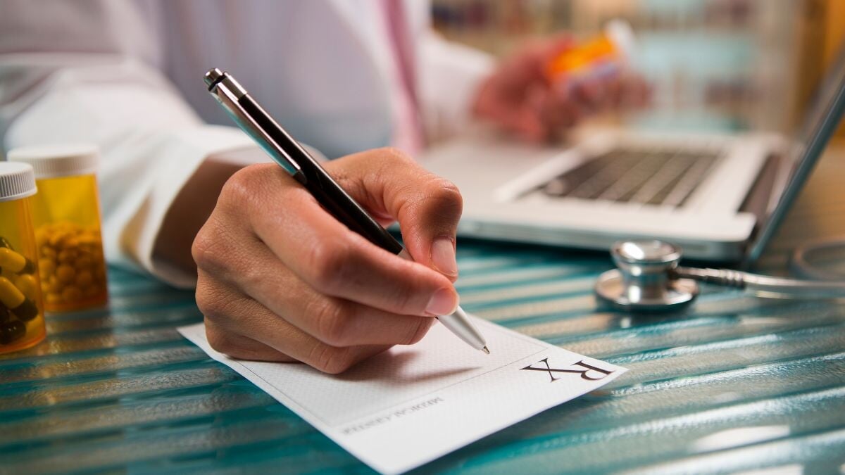 un homme écrivant avec un stylo sur un morceau de papier