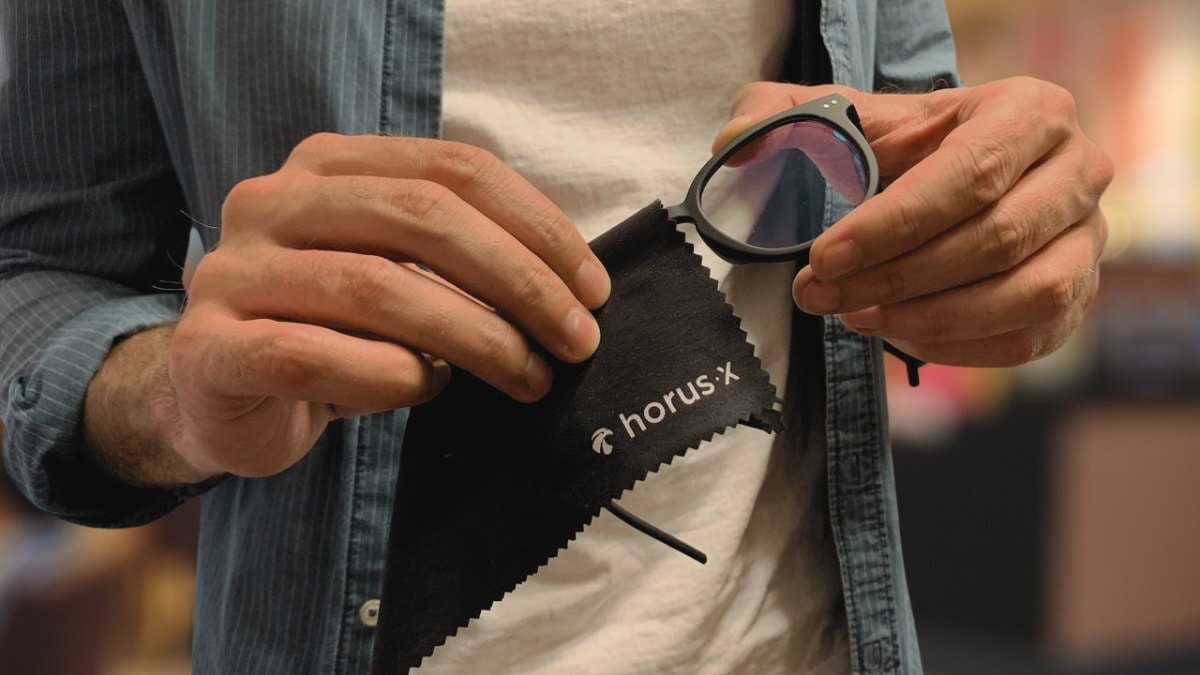 un homme nettoie ses lunettes Horus X avec un chiffon en microfibre
