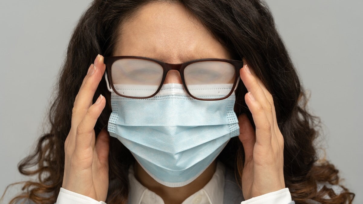 une Femme d'affaires avec des lunettes embuées et un masque facial