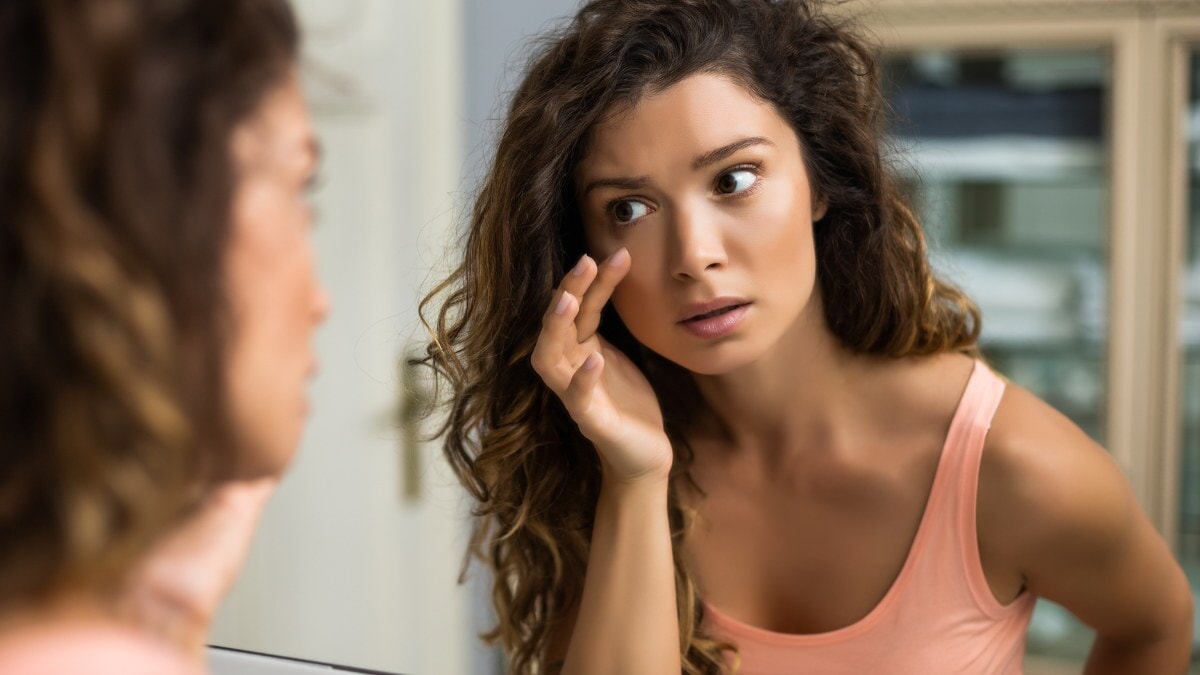 une femme regardant ses poches sous les yeux dans le miroir